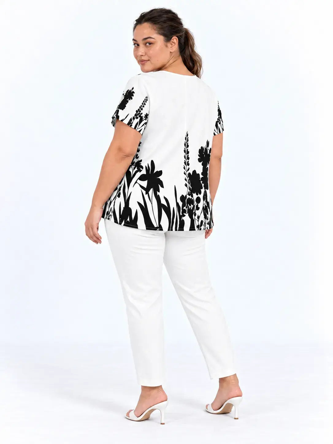 Vista de costas da blusa plus size branca com flores e folhagens pretas na barra e mangas curtas.