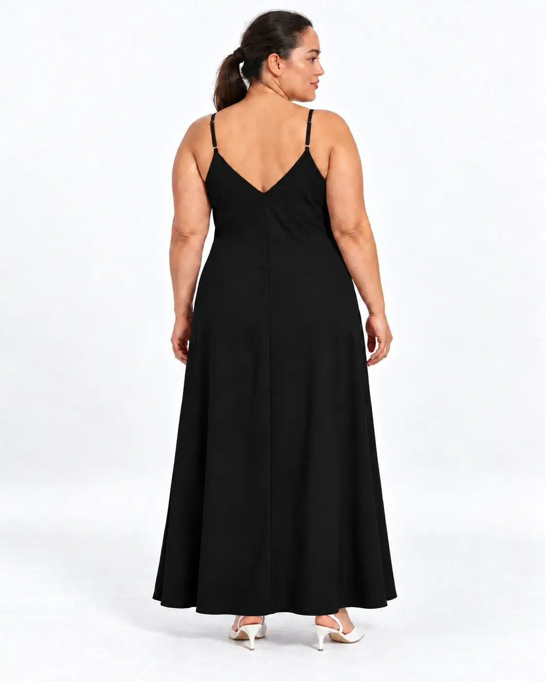 Vestido longo plus size preto visto de costas na modelo, com alças finas, decote em V e parte posterior lisa.