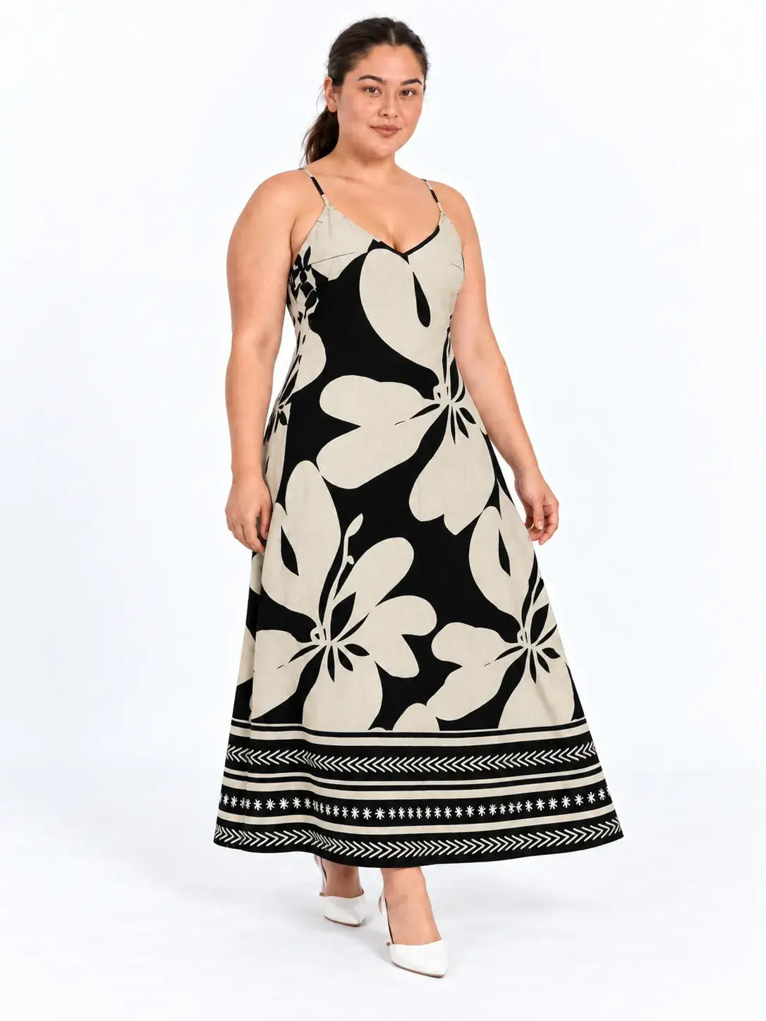 Modelo dando um passo com vestido longo plus size floral boho bege e preto, mostrando o movimento da barra.
