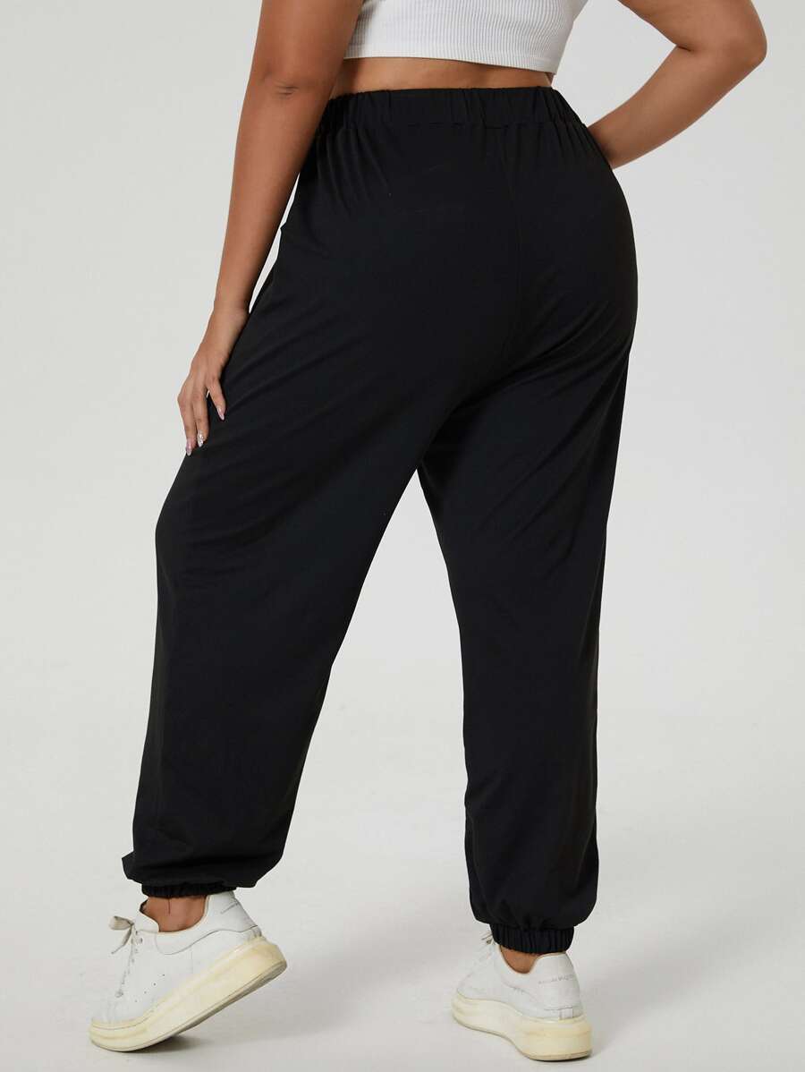 Calça jogger plus size preta, com nó frontal, modelagem confortável e tecido macio. Ideal para looks versáteis e modernos.