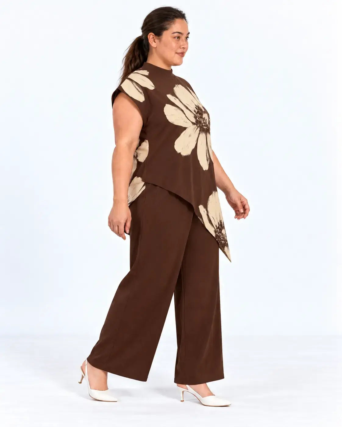 Vista lateral da blusa plus size castanha com flores bege, mostrando o caimento solto e a barra assimétrica.