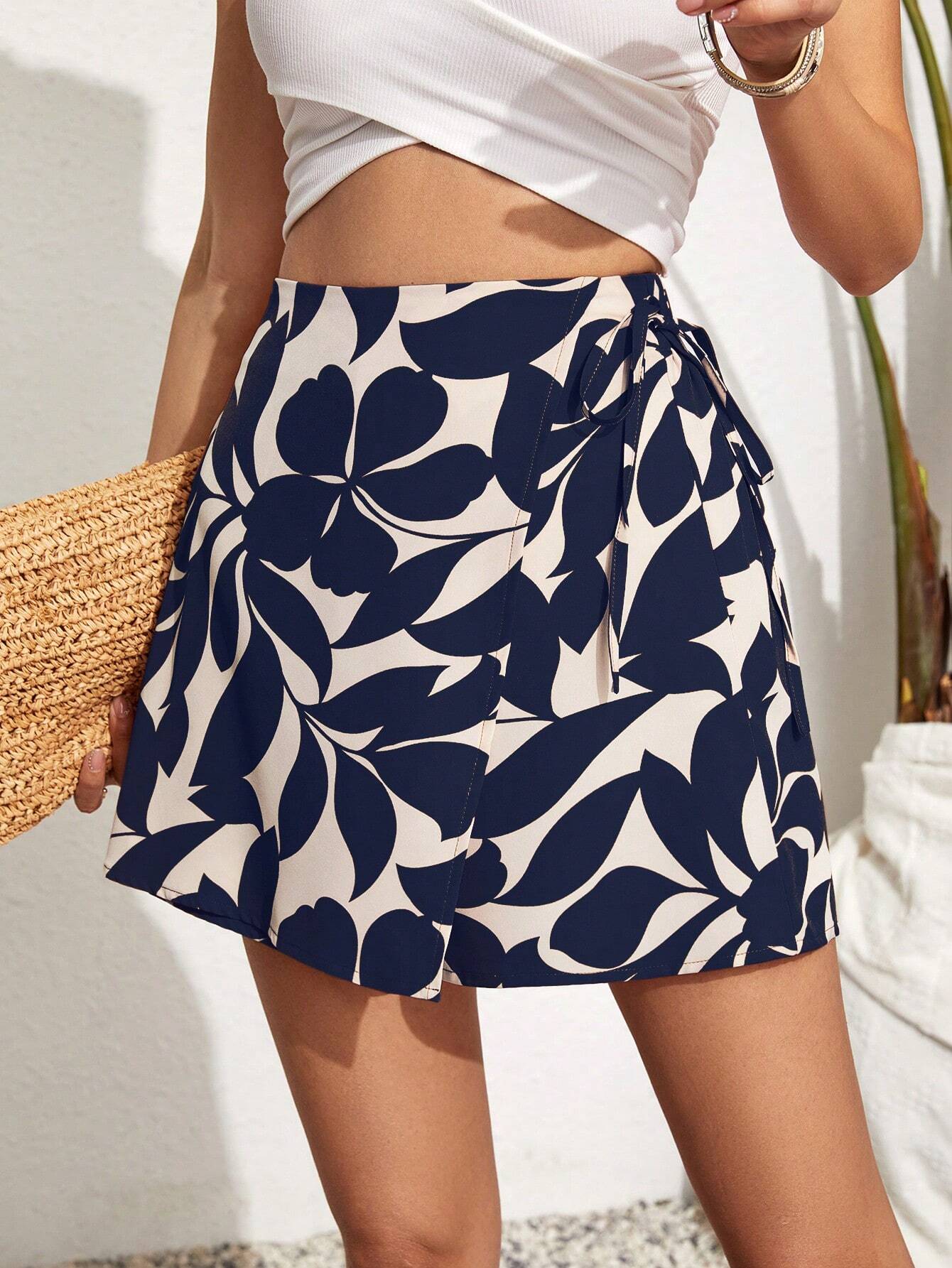 Shorts feminino com estampa tropical, tecido leve de algodão e elastano. Design moderno com detalhes cruzados, bolso prático e ajuste confortável.

