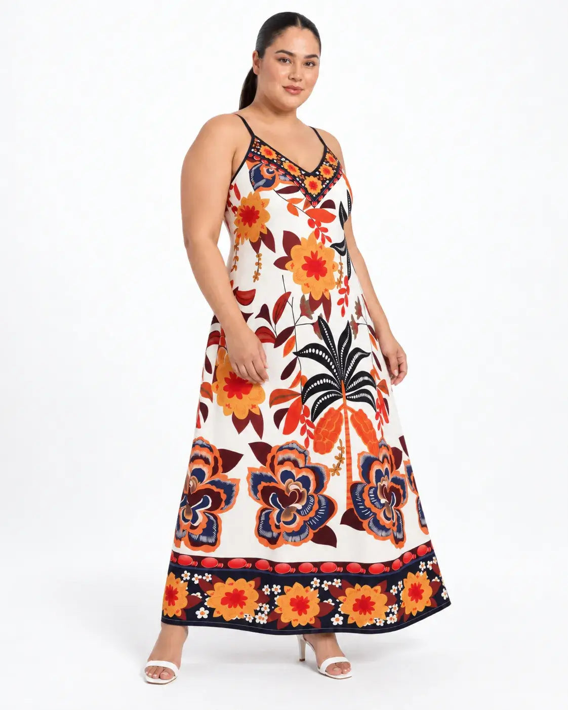 Vista em três quartos do vestido longo plus size com estampa botânica multicolorida, alças finas e barra ampla.