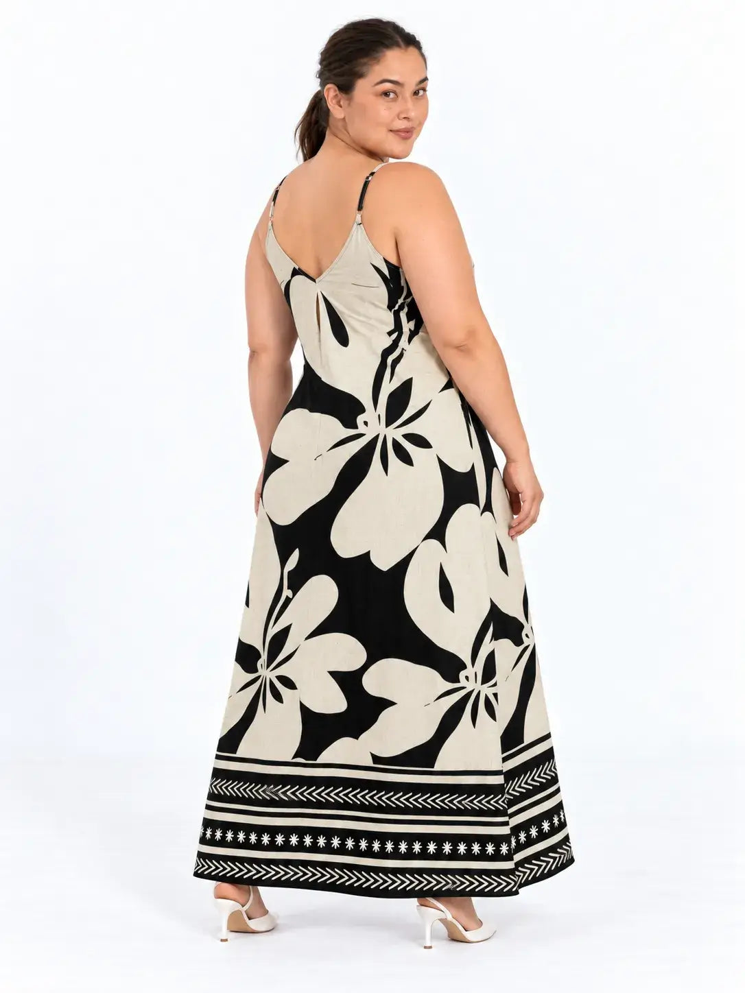 Vista de costas do vestido longo plus size floral boho bege e preto, com alças finas e faixas geométricas na barra.