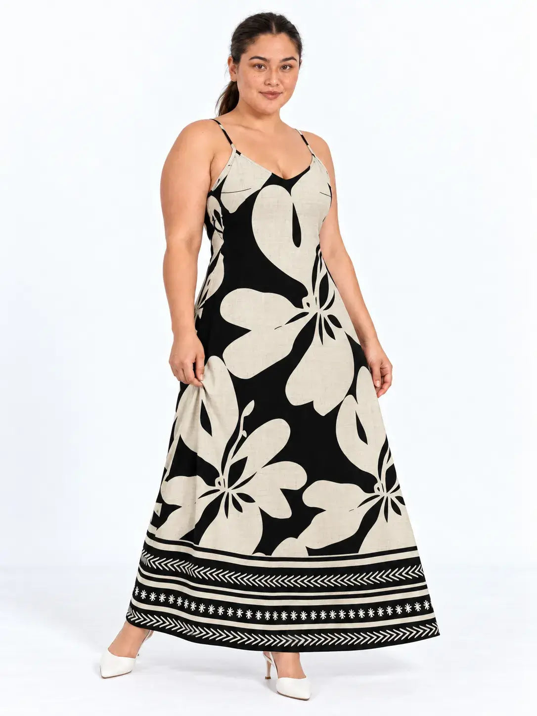Modelo de frente usando vestido longo floral boho bege e preto, com um pé para o lado e a saia levemente aberta.